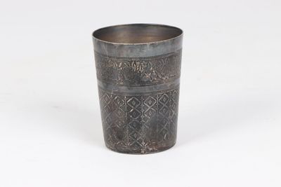 an old metal cup with a design on the rim