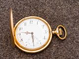 une montre de poche en or posée sur une surface marron
