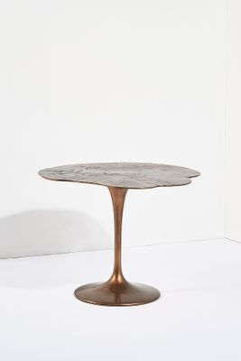 une table ronde avec un piètement en métal et un plateau en marbre