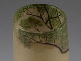 a small vase with a tree on it on a table