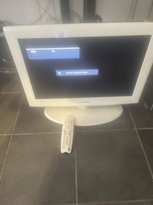 a computer monitor sitting on the floor with a remote control