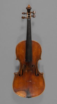 an old violin sitting on top of a table next to a gray wall