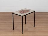 une petite table avec un plateau en carrelage posée sur un plancher en bois
