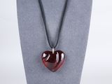 a red heart shaped glass pendant on a black cord necklace