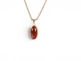 a gold necklace with a red stone pendant on a gold chain