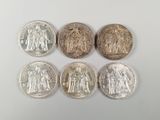 un groupe de cinq pièces d'argent posées sur une surface blanche