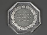 an old silver coin with a wreath around it on a black surface