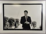 photographie en noir et blanc d'un homme en costume debout devant un groupe de femmes