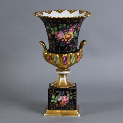 un vase décoré de fleurs, posé sur un socle, sur fond gris