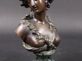 a bronze busturine of a woman with a flowered head