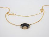 a black and gold necklace with a coin on a gold chain