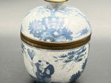 a blue and white jar with a lid on a table