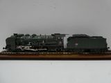 un train miniature posé sur un socle en bois, sur une surface blanche