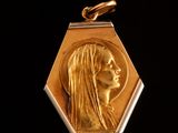 l'image d'une médaille d'or sur laquelle figure le visage d'une femme