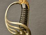 a sword with a gold handle on a gray surface