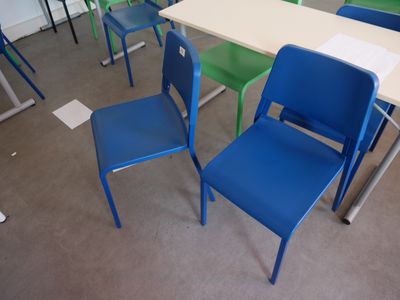 many chairs and tables in a classroom with a white table