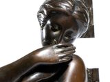 a bronze statue of a woman with her hands on her face