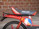 a red and black motorcycle parked in front of a brick wall