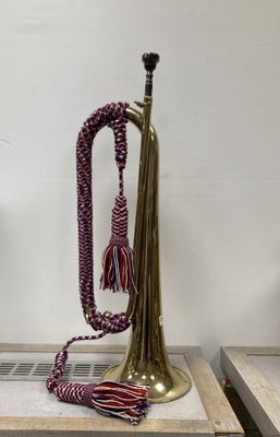 a brass trumpet sitting on top of a table next to a vase