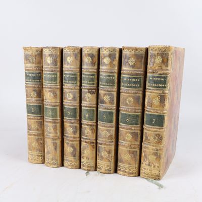 six vieux livres sont alignés sur une surface blanche