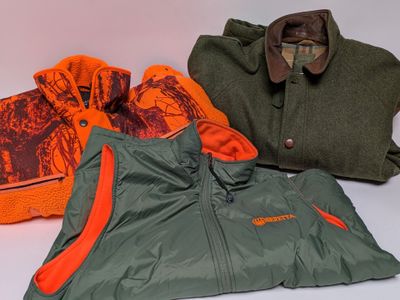 three jackets and a hat sitting on a table