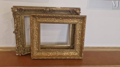 two picture frames sitting on a table with a clock in the background