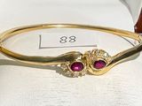 gold bangle with ruby stones and diamonds on display in a jewelry box