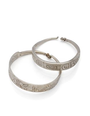 une paire de boucles d'oreilles créoles en argent sur fond blanc
