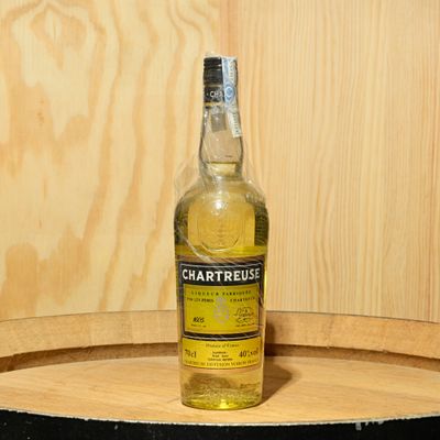 a bottle of alcohol sitting on top of a wooden barrel