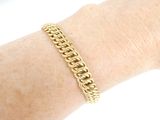 someone is wearing a gold chain bracelet on their arm
