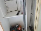 un aspirateur dans un coin de la salle de bains, la porte ouverte