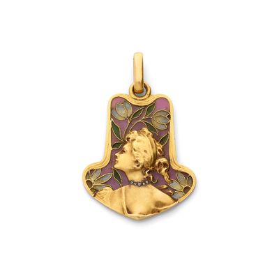un pendentif en or orné d'un visage de femme et de feuilles