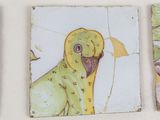 three paintings on the wall of a bathroom with a parrot