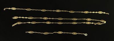 four pieces of gold colored metal with a chain on a black background