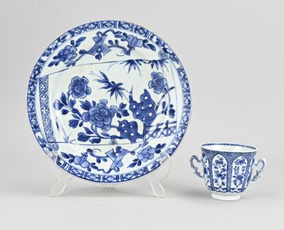 a blue and white plate with a cup and saucer on a stand