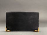a black leather wallet with gold accents on a gray background