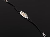 a close up of a watch on a black surface with a black background
