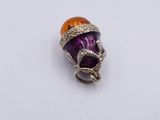 a close up of a purple and orange glass bead on a white surface