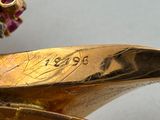 a close up of a gold plated object with a flower on top of it