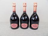 three bottles of champagne sitting on top of a table next to each other