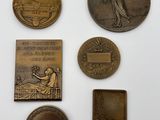 six bronze medals and a plaque on a white surface
