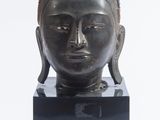 statue représentant une tête de Bouddha posée sur un socle en marbre noir