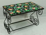 table en fer forgé avec un plateau en carreaux colorés, posée sur un sol blanc