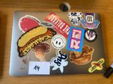 a laptop covered with stickers and magnets sitting on a table