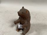 une petite figurine d'ours assise par terre, avec une étiquette de prix