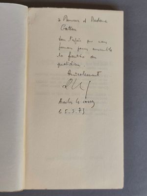 un livre ouvert, sur lequel est posée une note manuscrite, posé sur une table