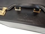 a black briefcase with a gold handle on a white surface