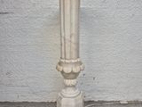 a white vase on the ground next to a white wall