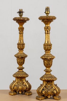 une paire de bougeoirs anciens en laiton posés sur une table en bois