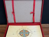 a red box with a compass on it on a wooden table